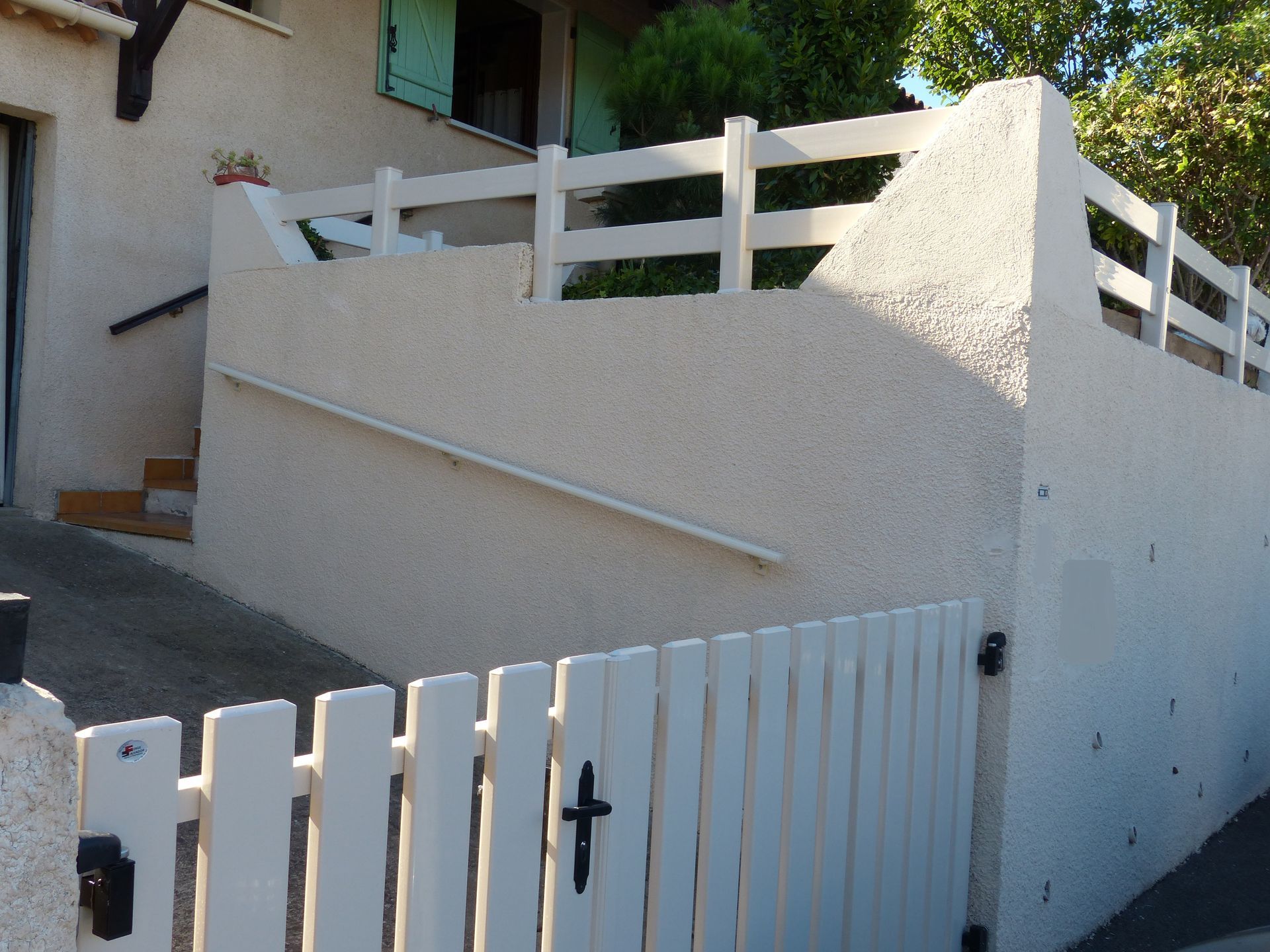 Angle d'un muret avec une rambarde blanche et un portillon