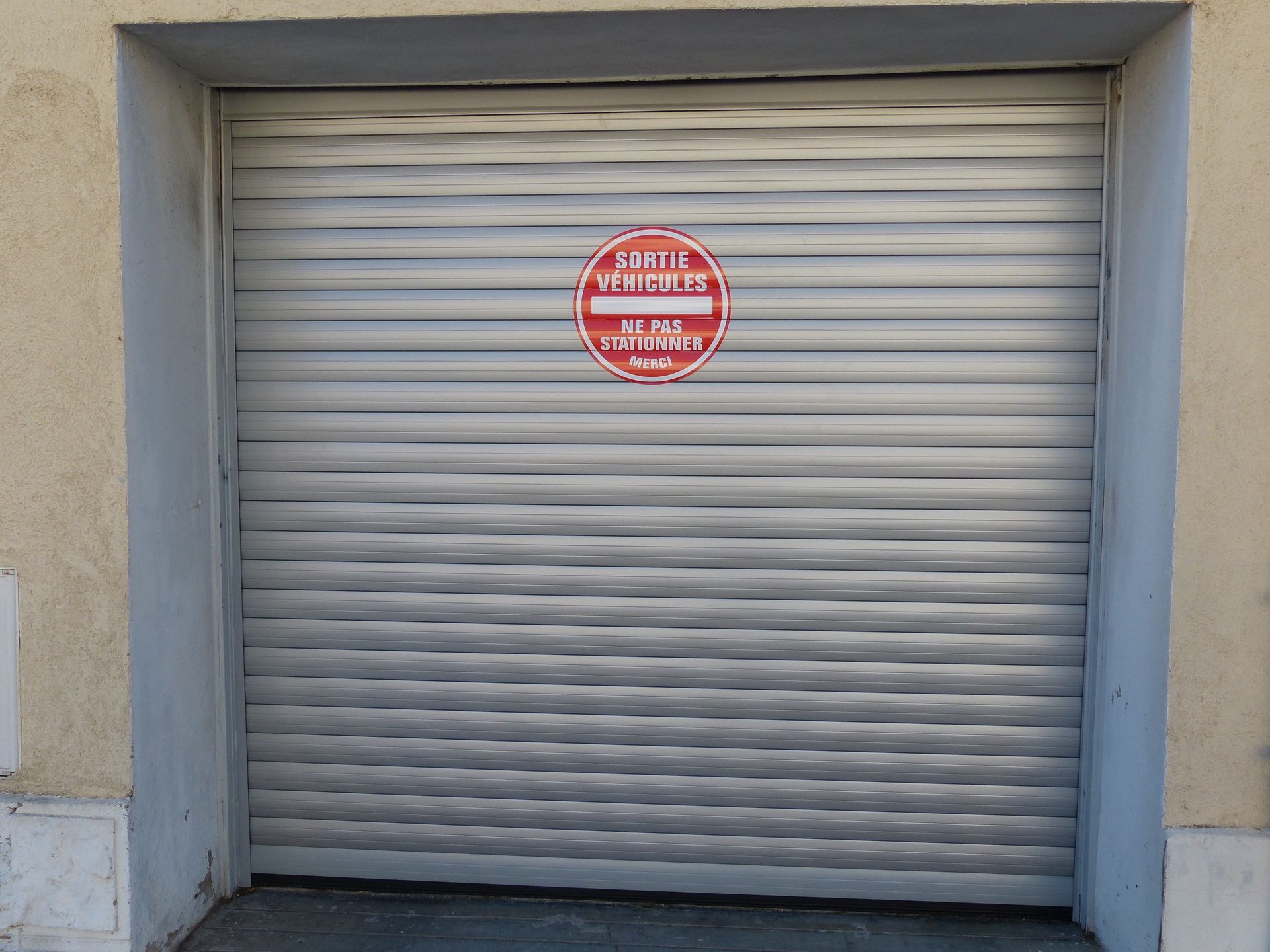 Porte de garage fermée avec le panneau : sortie de véhicule