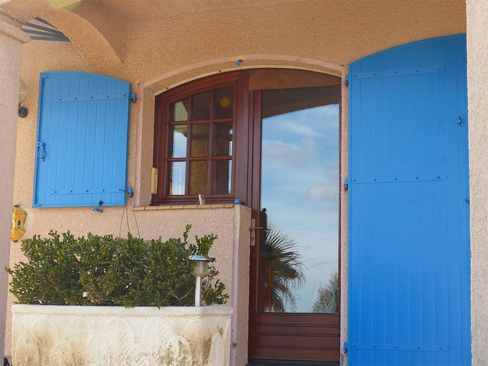 Baie vitrée avec des volets couleur azur