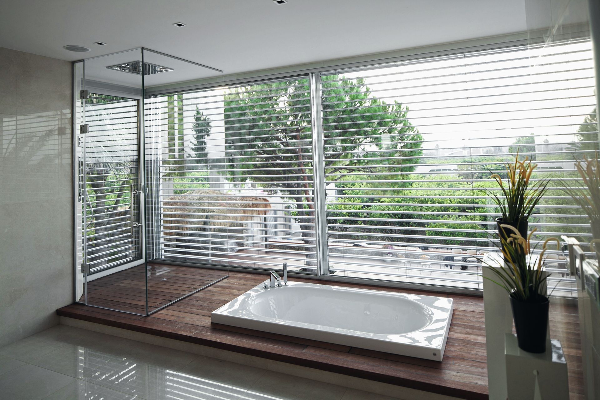 Bagno moderno con vasca, doccia in vetro e ampia finestra con vista sul verde.