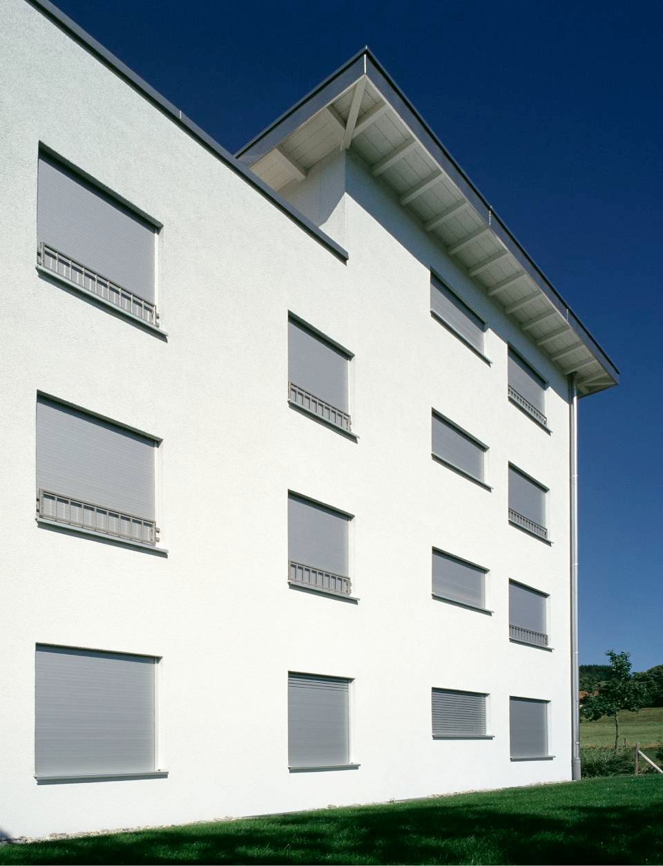 Edificio bianco con persiane grigie contro un cielo azzurro e terso.