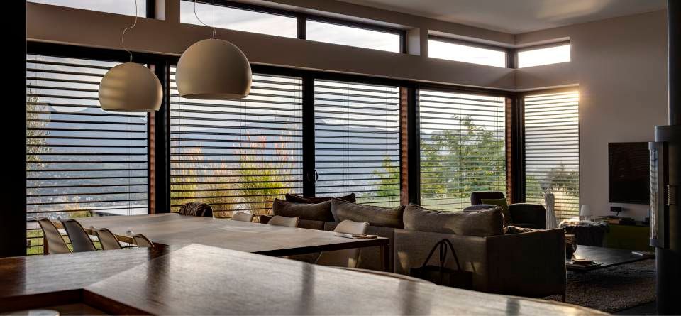 Interni moderni con ampie finestre, lampadari e vista sulle montagne.