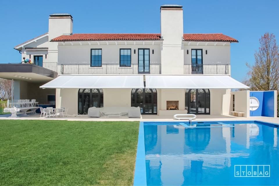 Casa moderna con piscina e area salotto all'aperto, sullo sfondo del cielo azzurro.