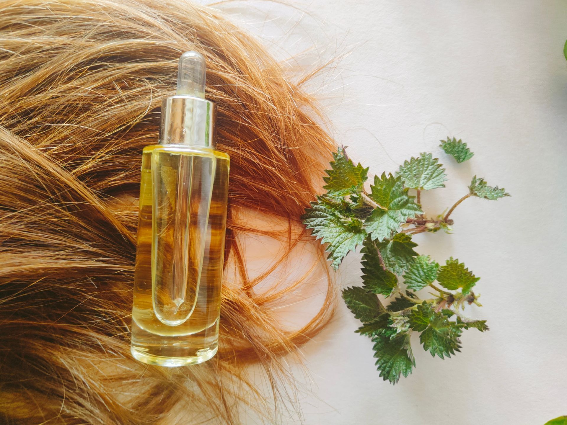 Flacon d'huile essentielle posé sur une mèche de cheveux