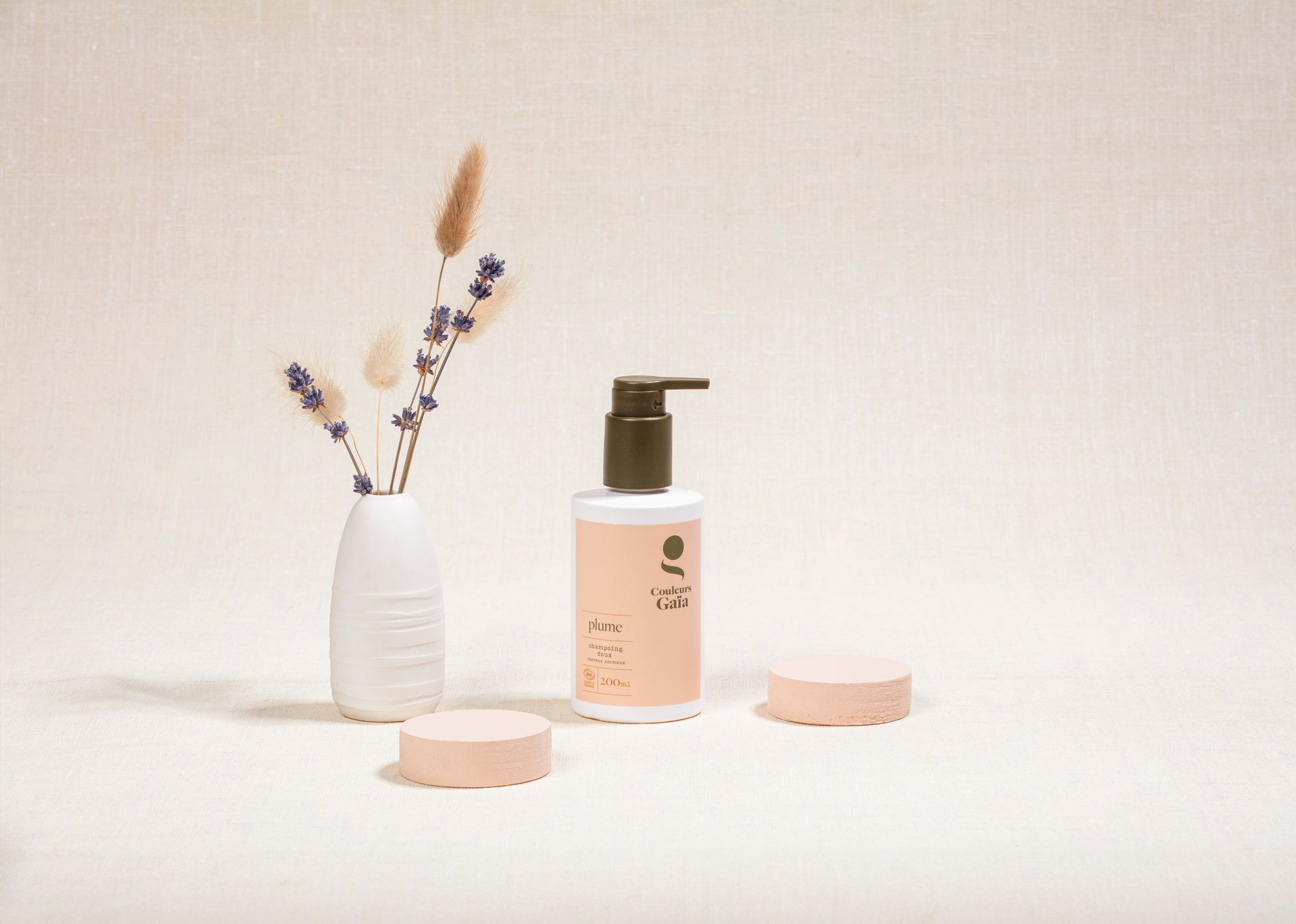 Shampoing Plume de Couleurs Gaïa à côté d'un vase avec des plantes séchées