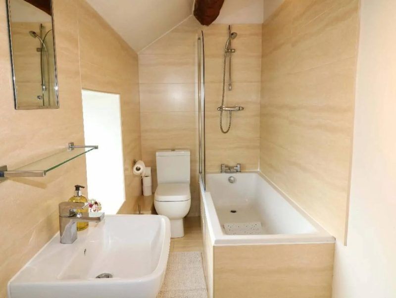 Small beige bathroom with sink, toilet, tub, and shower.