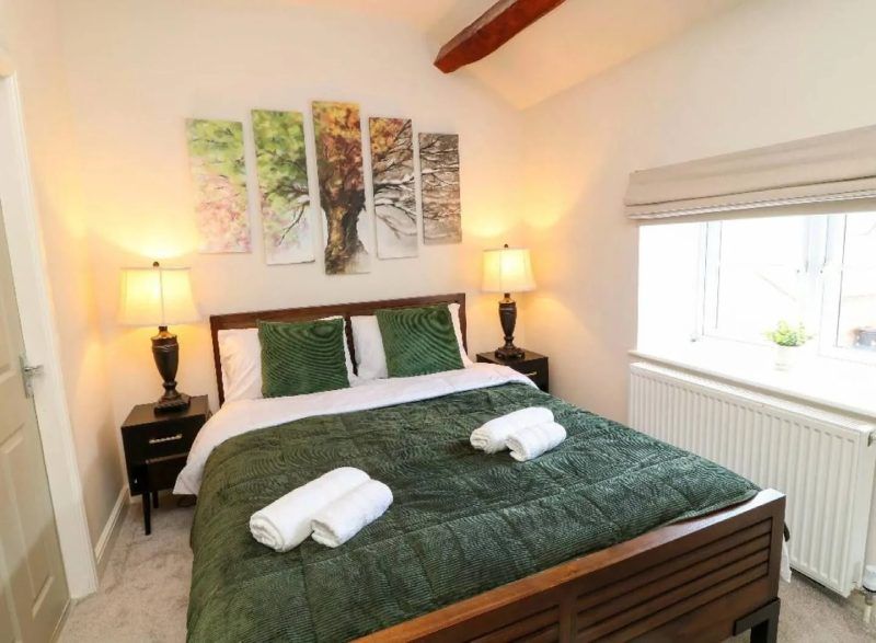 Bedroom with a bed, nightstands, lamps, artwork, window, and radiator.