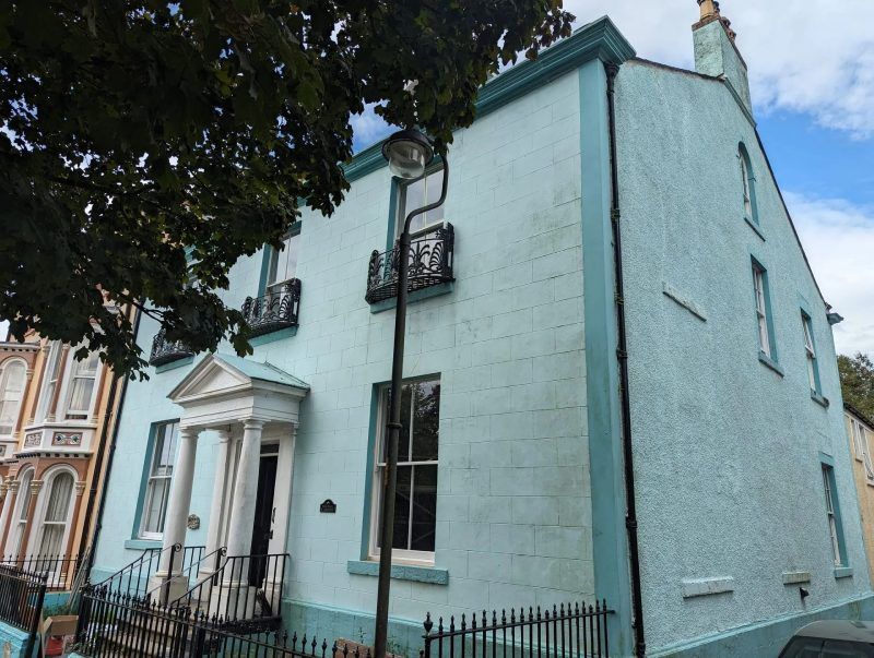 Light blue building with black railings, windows, and decorative balconies.