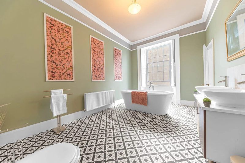 Bathroom with a freestanding tub, patterned tile floor, and sage green walls.