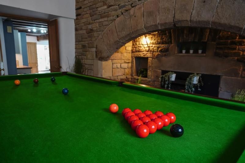 Pool table with red and black balls, green felt, and stone archway in background.