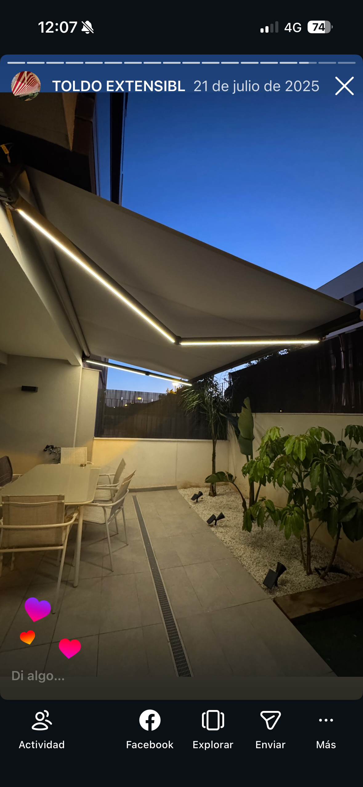 Patio con toldo retráctil, asientos al aire libre y pequeño jardín al anochecer.