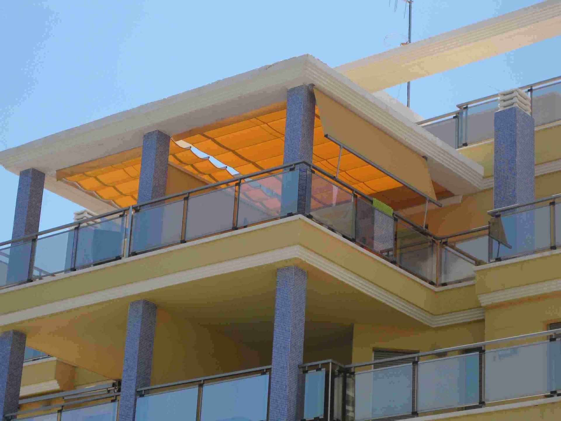 Un balcón con un toldo amarillo encima.