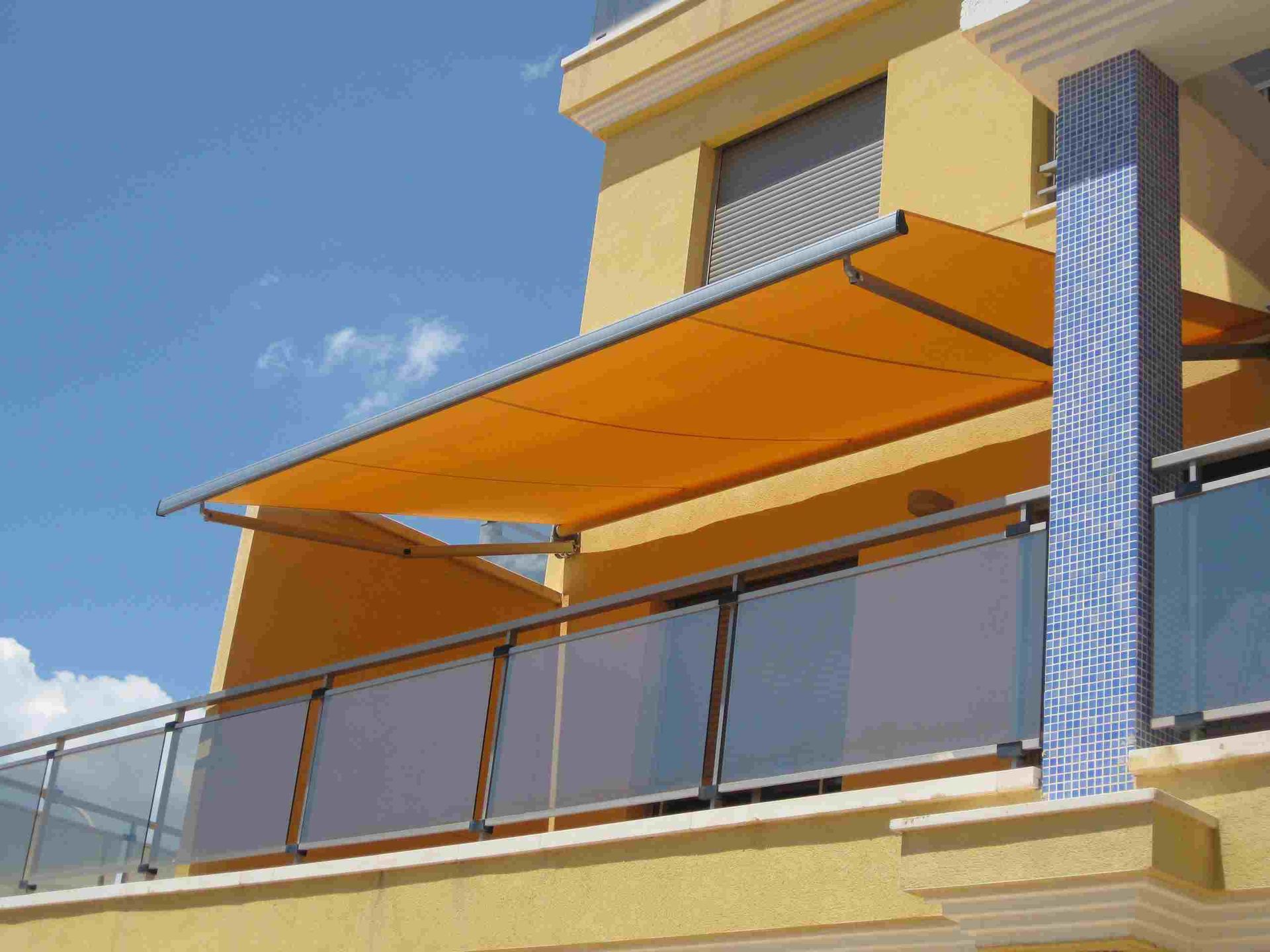 Un balcón con un toldo amarillo encima.