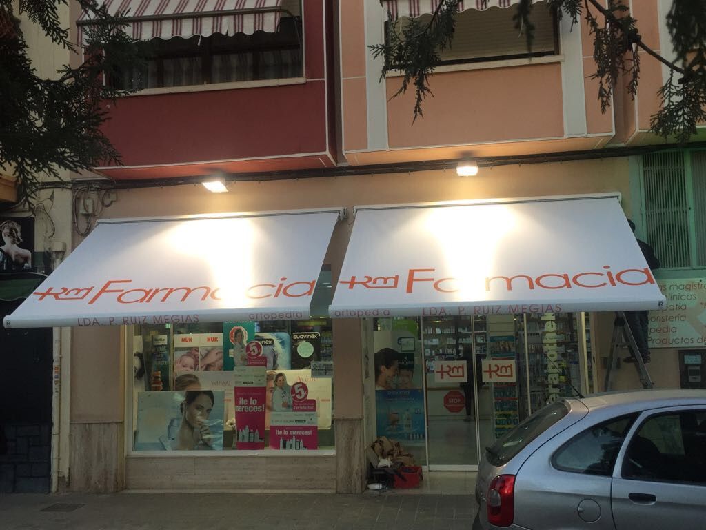 Una farmacia con un coche aparcado delante.