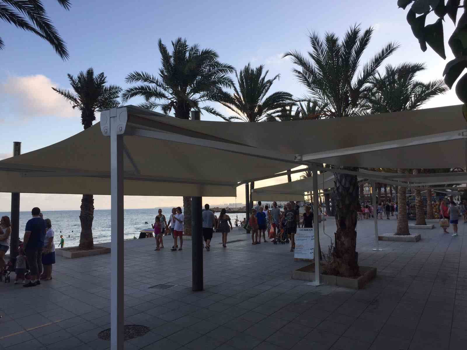 Un grupo de personas de pie bajo sombrillas cerca del océano.