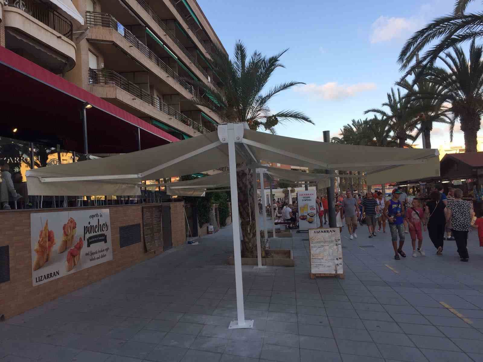Un gran paraguas blanco está sobre la acera frente a un edificio.