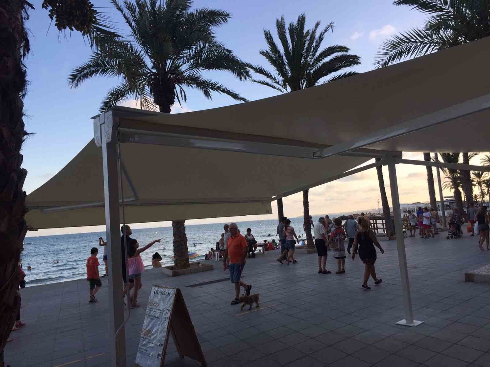 Un grupo de personas de pie bajo un toldo cerca del océano.