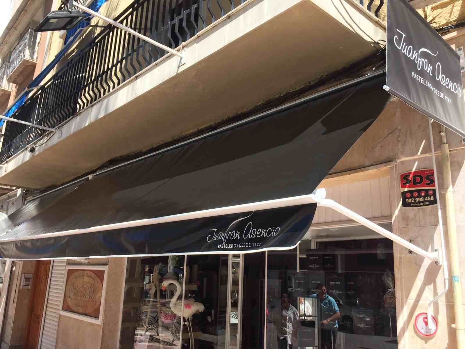 Un escaparate con un toldo negro y un cartel que dice sos