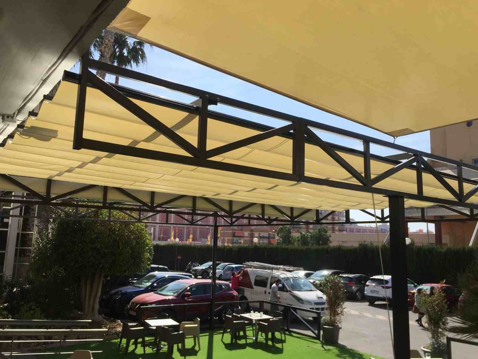 Un estacionamiento con mesas y sillas bajo un dosel.