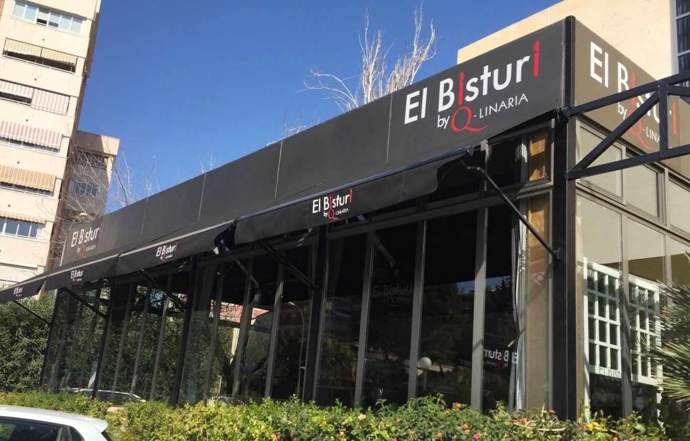 Un coche está aparcado delante de un edificio con un cartel que dice el b stur.