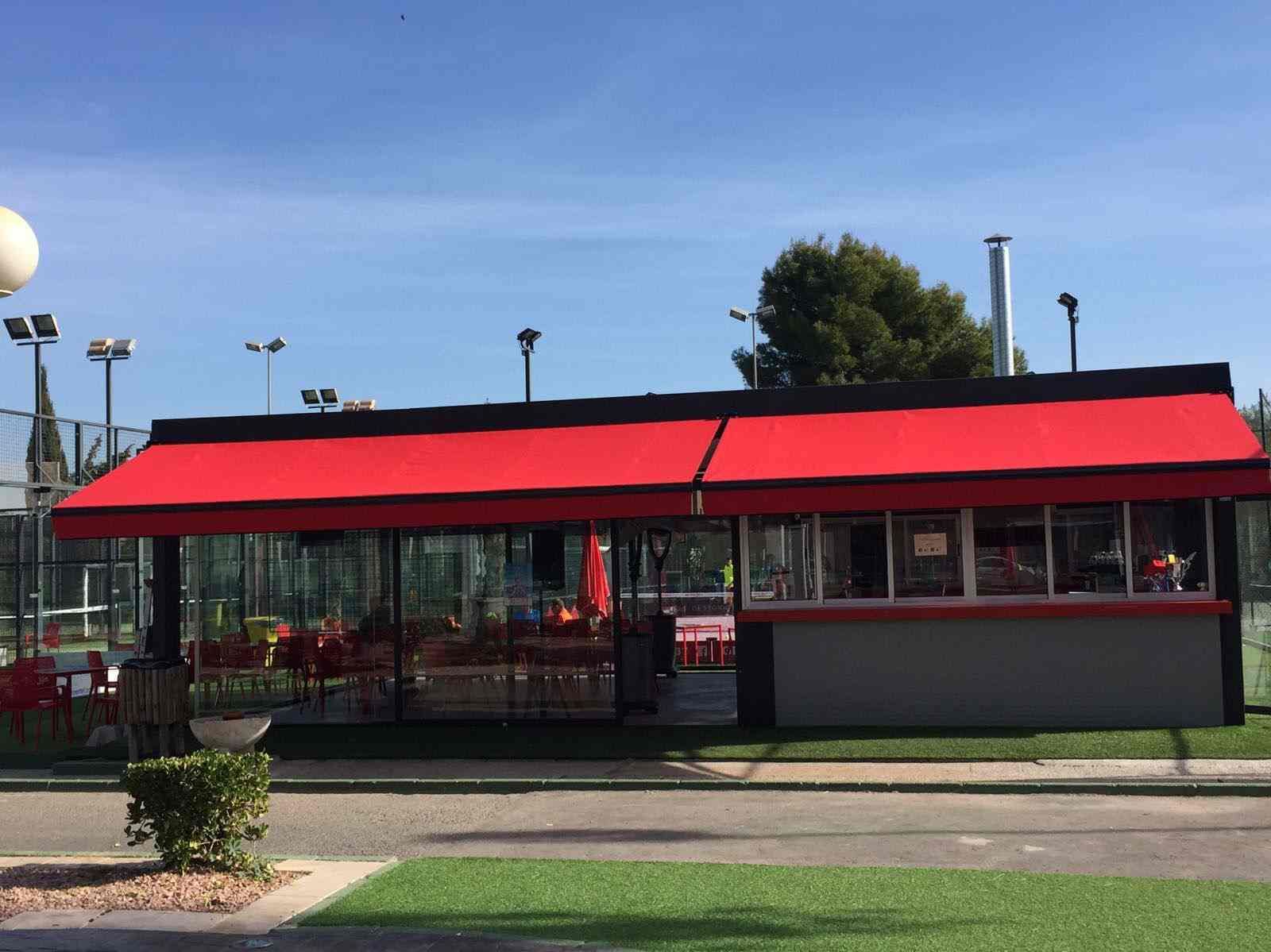 Un restaurante con un toldo rojo al costado.