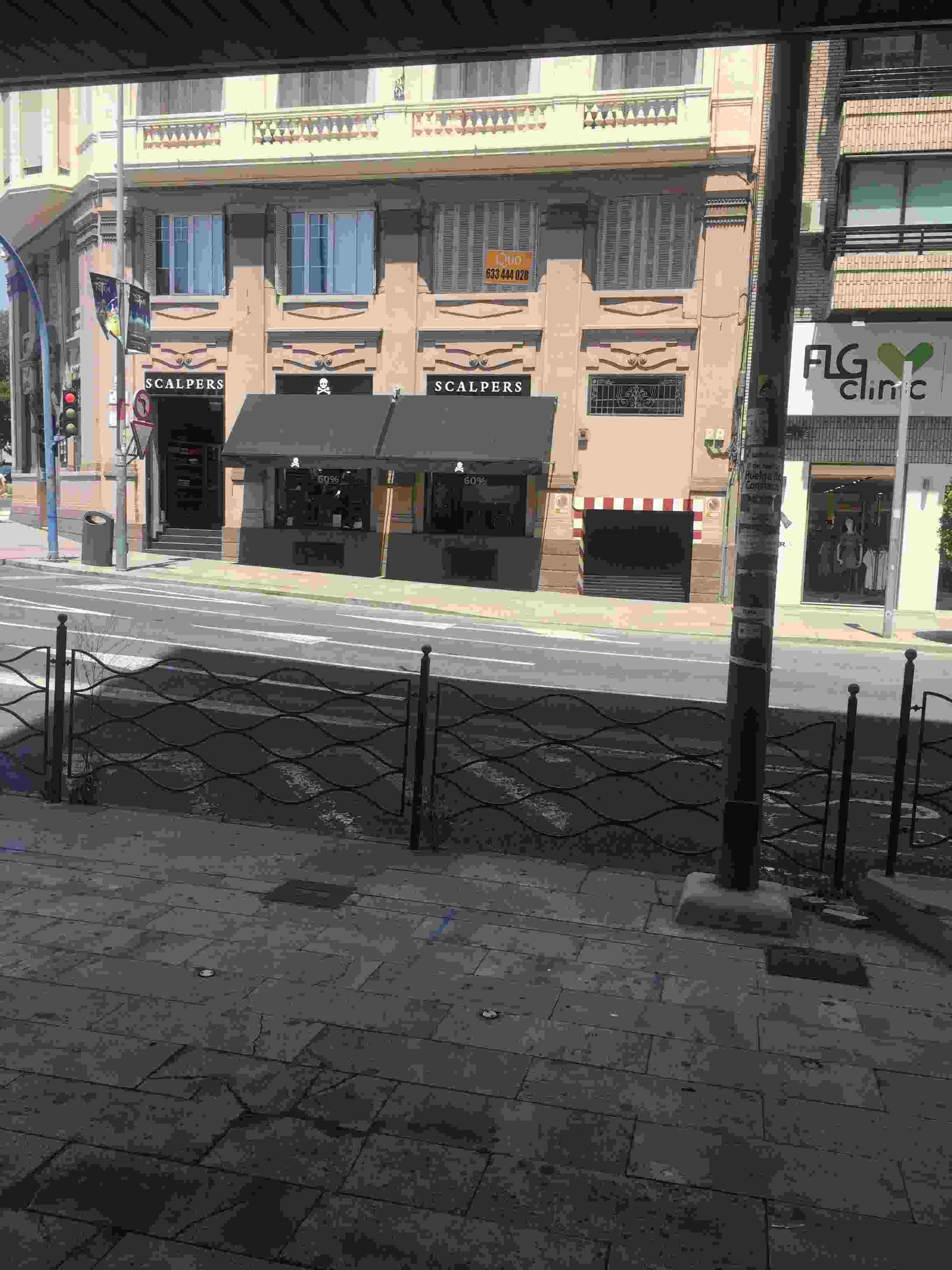 Una foto en blanco y negro de una calle de la ciudad con un cartel que dice alga