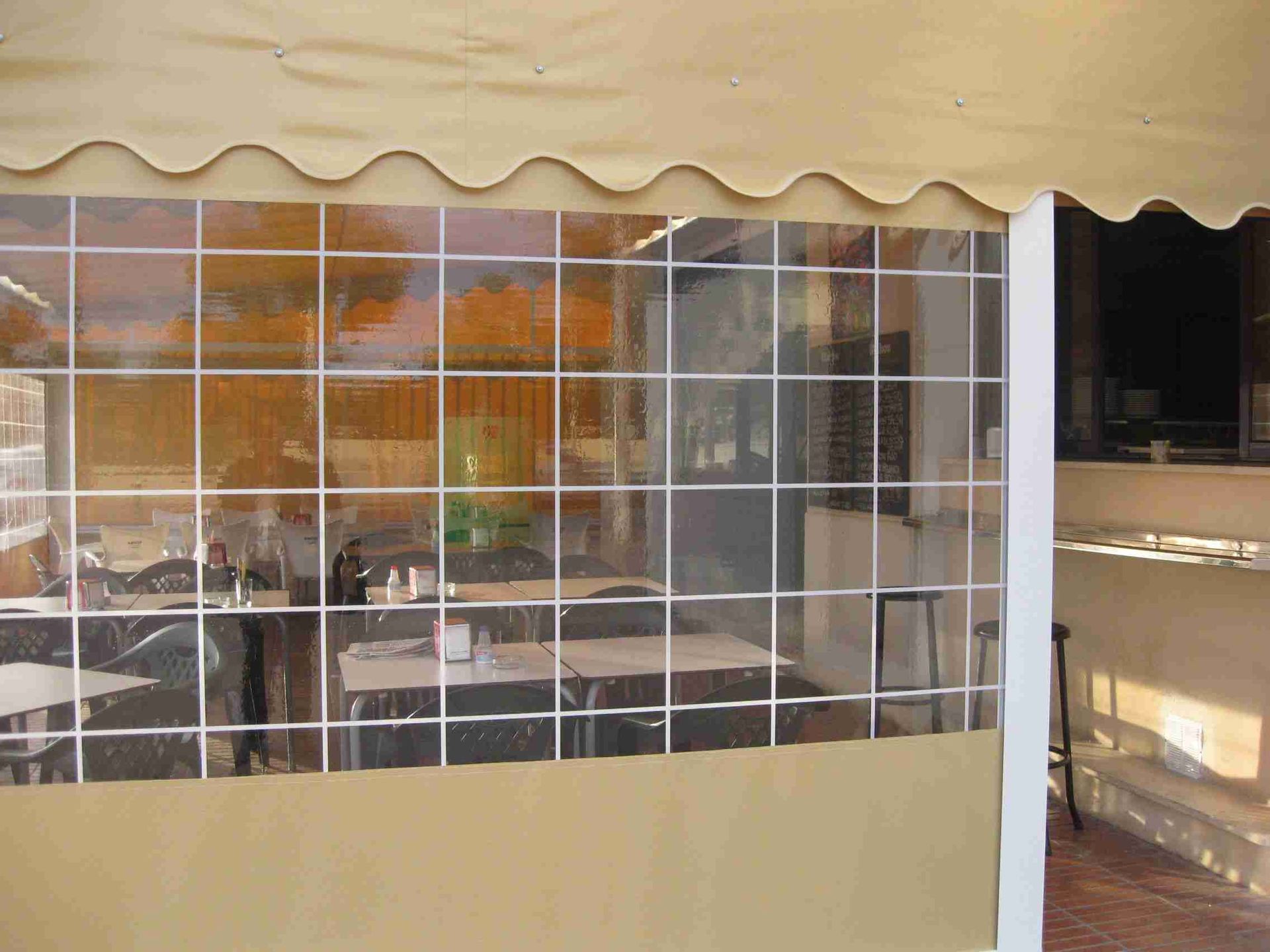 Un restaurante con mesas y sillas bajo un toldo transparente.