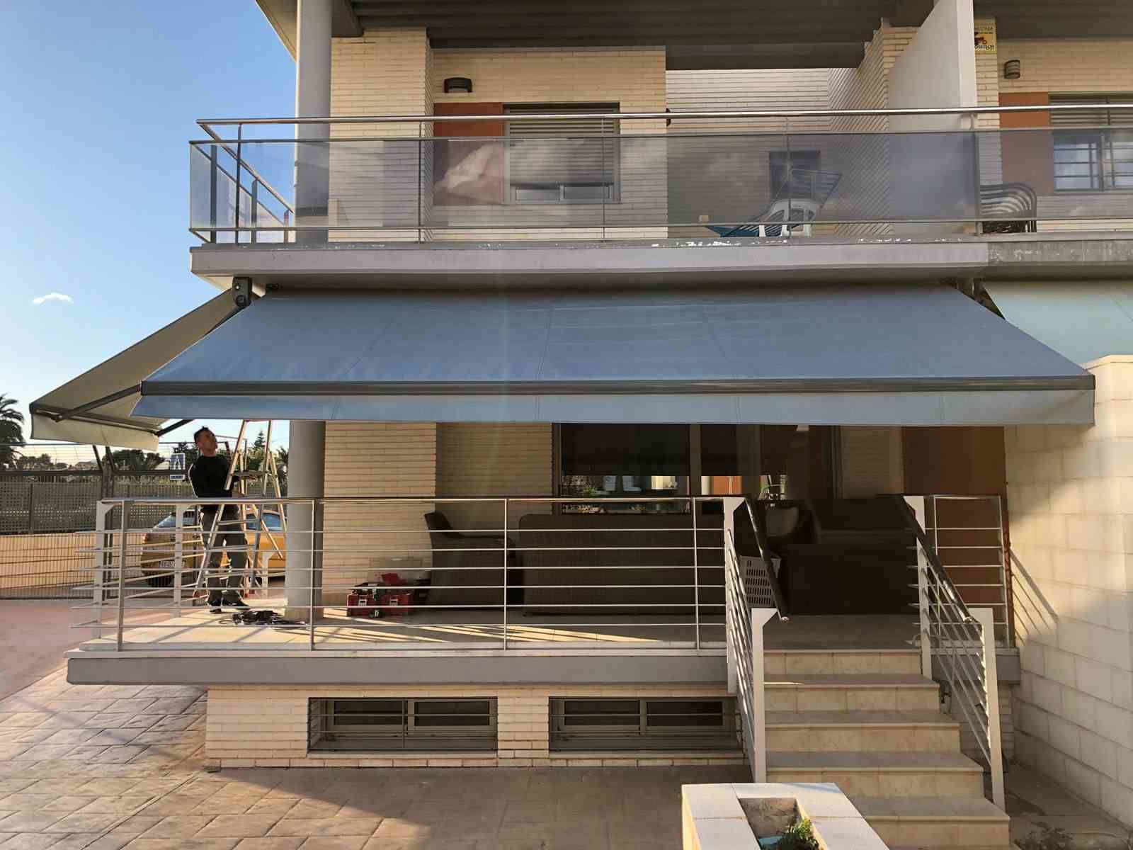 Un hombre está parado en una escalera frente a una casa con balcón y escaleras.