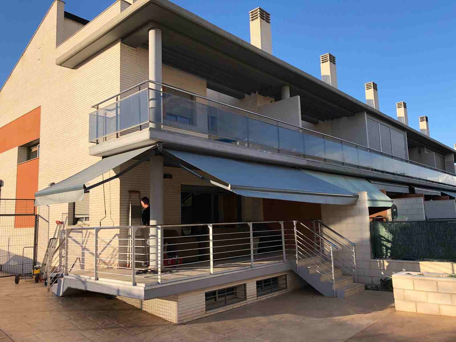 Una casa grande con balcón y toldo.