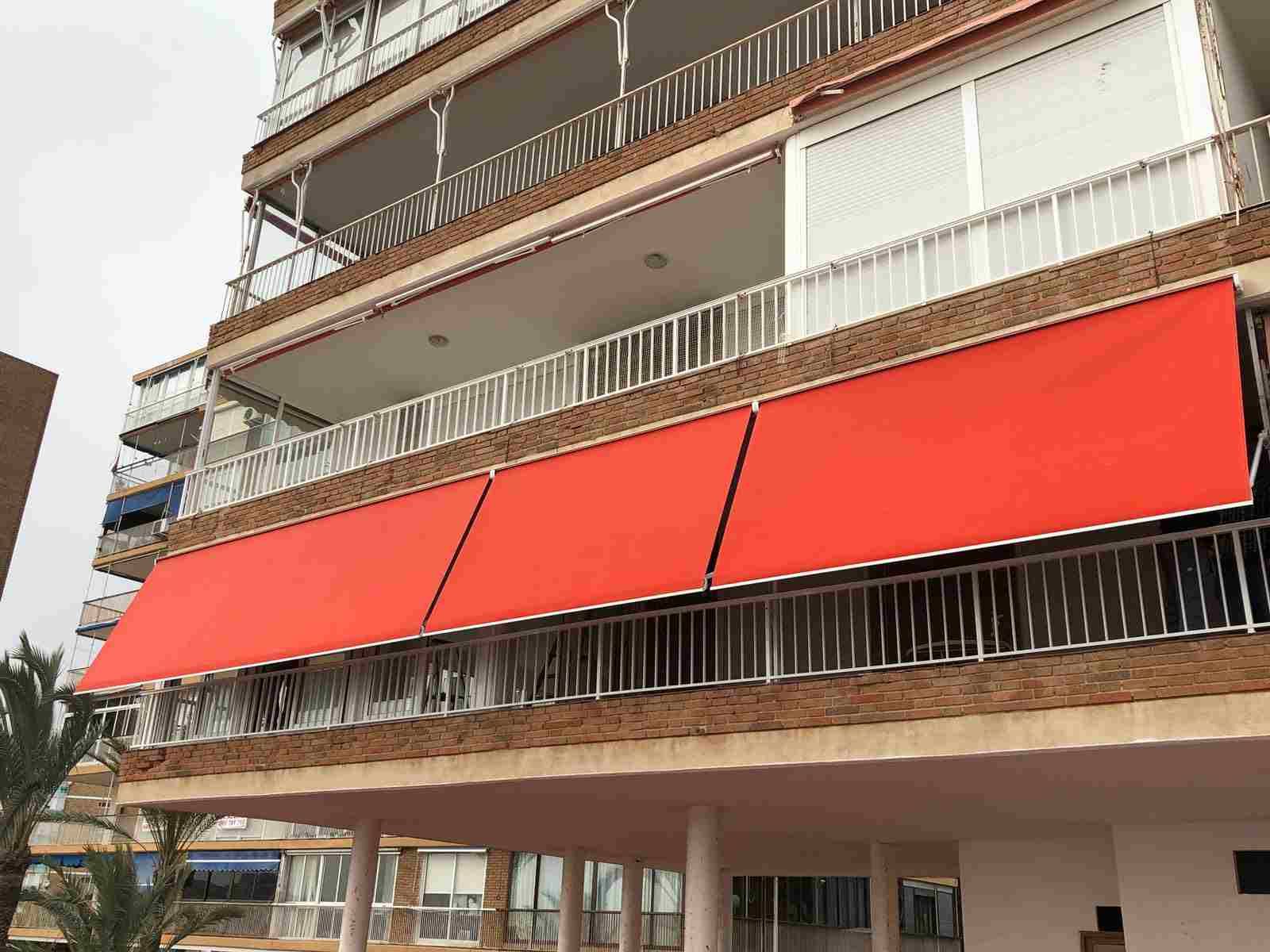 Un gran edificio con un toldo rojo en el balcón.