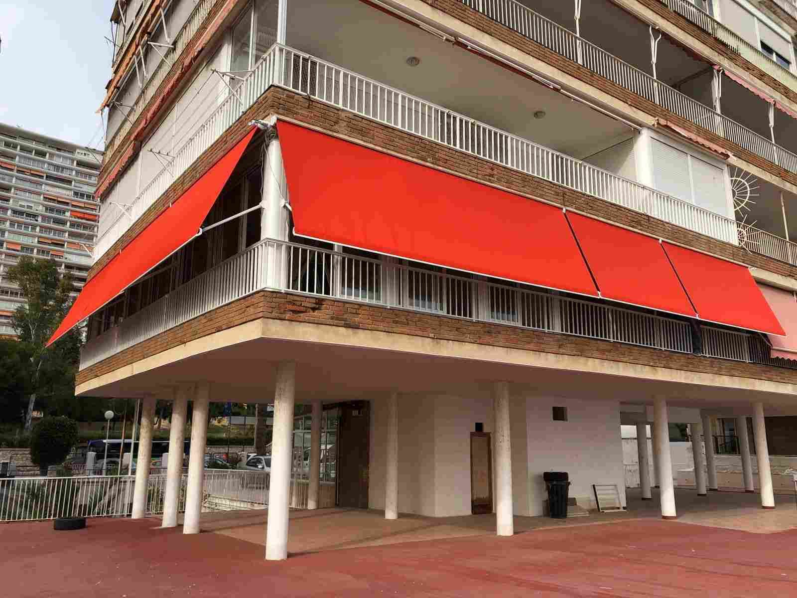 Un gran edificio con un toldo rojo en el balcón.