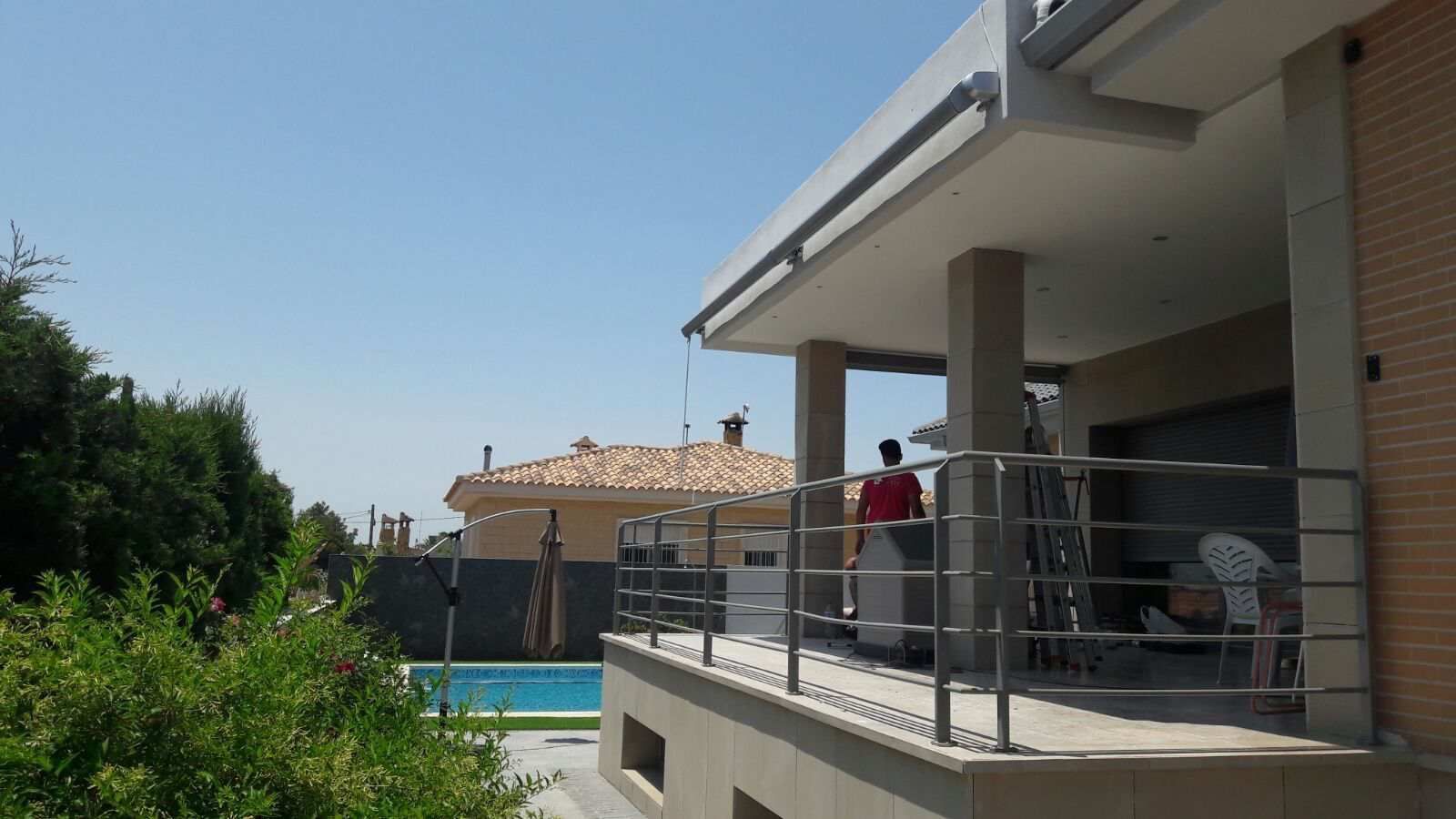 Un hombre de pie en un balcón con vistas a una piscina.