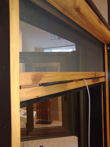 Una mujer abre una ventana en un dormitorio mientras una niña está sentada en una cama.