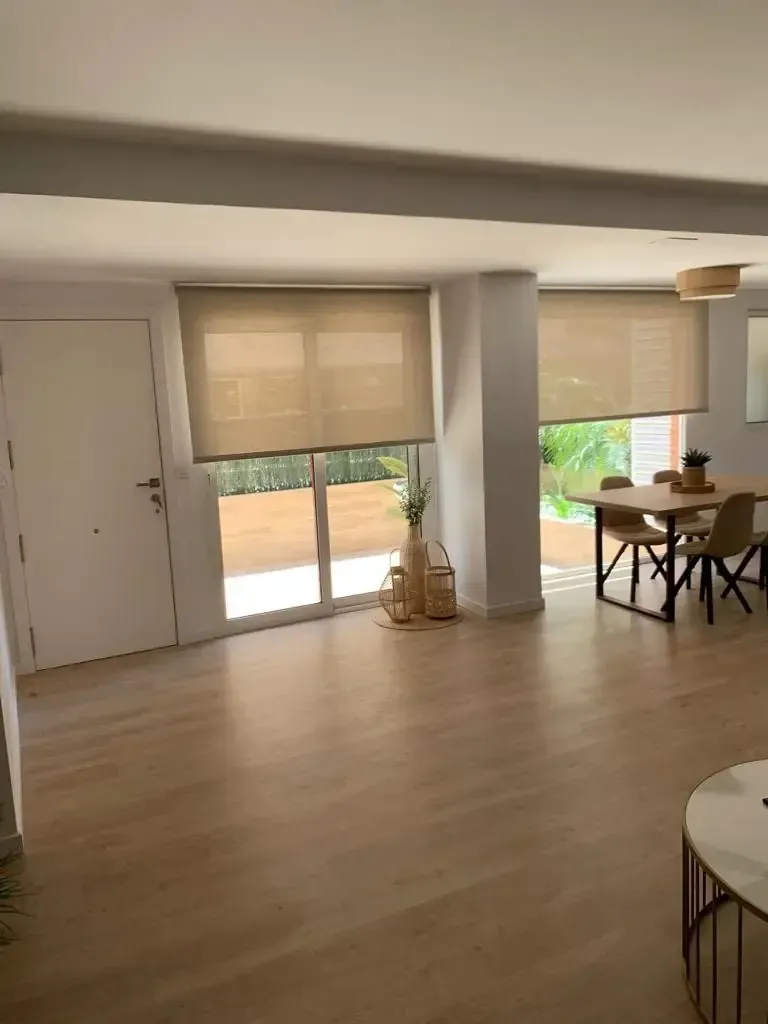 Exterior de un edificio comercial blanco con ventanas y puertas de vidrio oscuro.