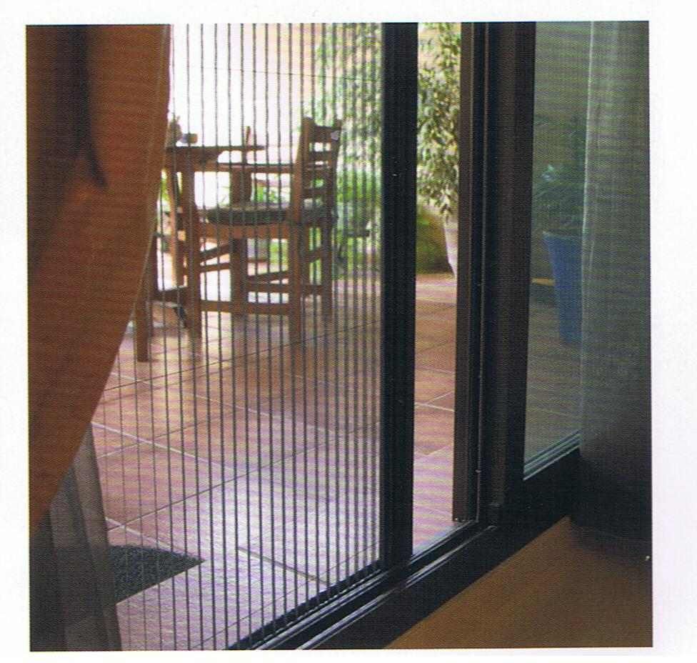 Una mujer está sentada en un sofá frente a una puerta corrediza de vidrio.