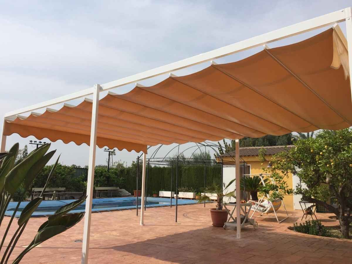 Toldo retráctil de color tostado sobre un patio, cerca de una piscina y un jardín, con marco blanco.