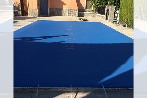 Una lona azul cubre una gran piscina.