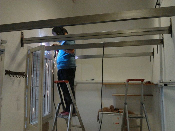Un hombre está de pie en una escalera trabajando en una estructura de metal.