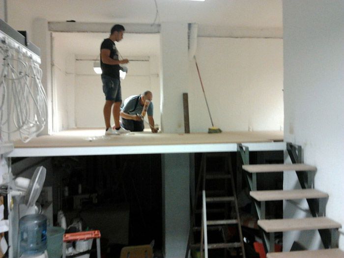 Dos hombres están trabajando en una escalera en una habitación.