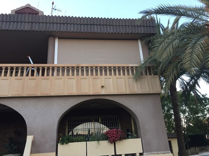 Una casa con un balcón y una palmera delante.