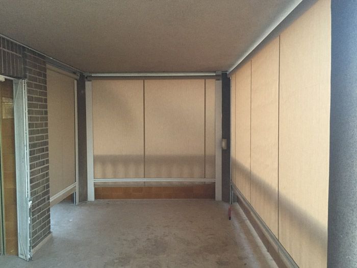 Una habitación vacía con una pared de ladrillos y persianas en las ventanas.