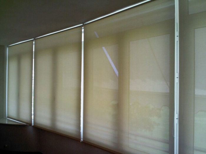 Una habitación con una hilera de persianas enrollables en las ventanas.