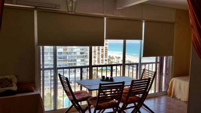 Una sala de estar con mesa y sillas y un balcón con vista al mar.