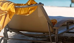 Una silla en la playa con una toalla amarilla encima.