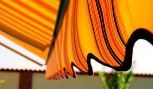 Un primer plano de un toldo de rayas naranjas y negras colgando de un techo.