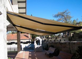 Un gran toldo cubre un patio con dos bancos debajo.