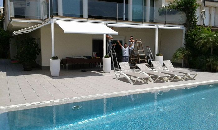 Un hombre está de pie en una escalera al lado de una piscina.