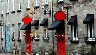 Una hilera de edificios de ladrillo con puertas rojas y toldos negros