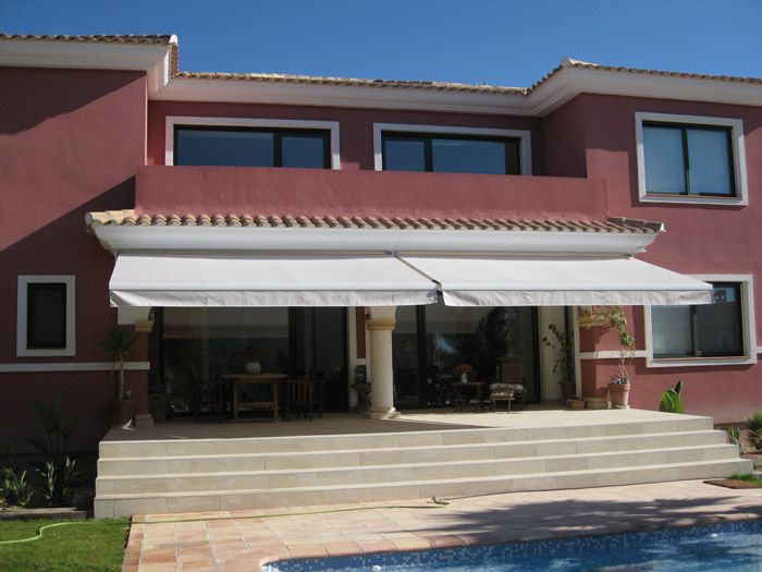 Una gran casa roja con un toldo blanco sobre el porche.