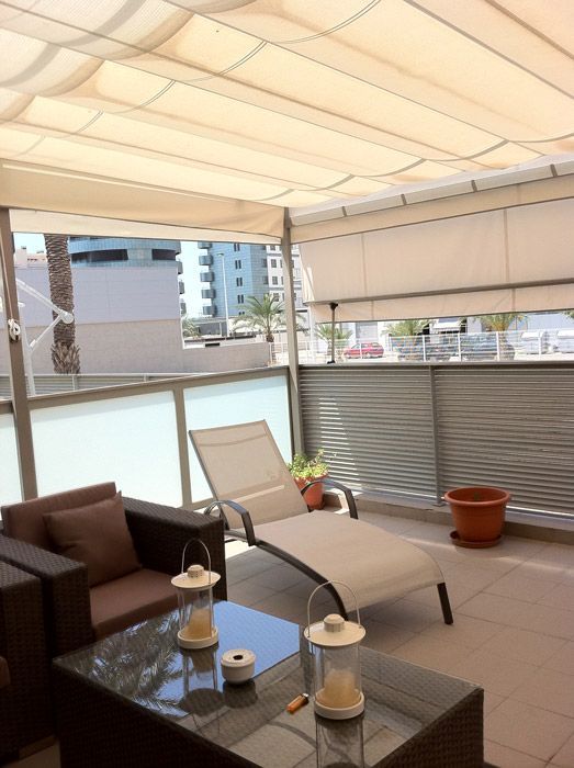 Un balcón con un sofá, una silla y una mesa.